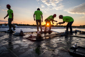Workers installing solar panels at sunrise